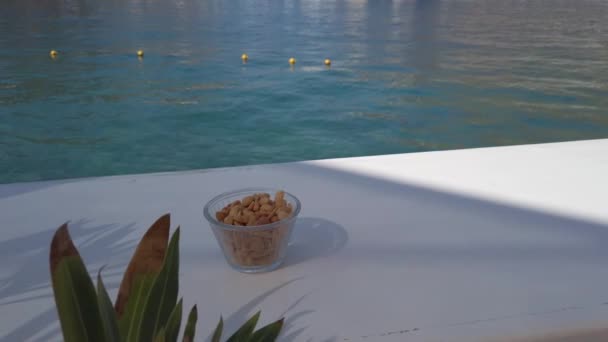 Ποτήρι λευκό κρασί στο τραπέζι κοντά στη θάλασσα — Αρχείο Βίντεο