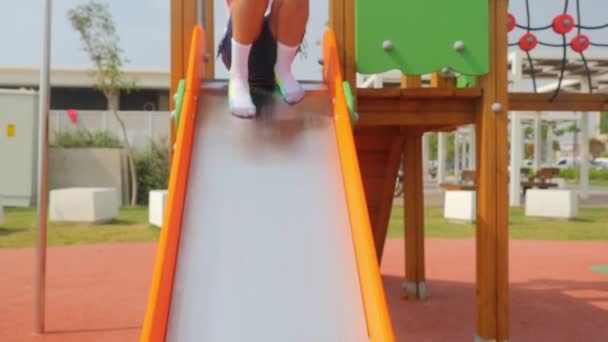 Girl happily sliding down on playground — 비디오
