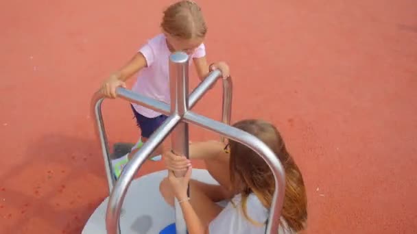 Two sisters playing on merry-go-round — Stock Video