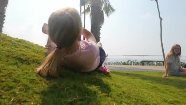 Tonårstjej rullar ner i gräset — Stockvideo
