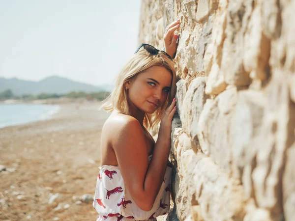 Mujer joven inclinada a la pared de piedra —  Fotos de Stock