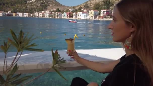 Mooie vrouw zitten in de waterkant met ananas sap — Stockvideo