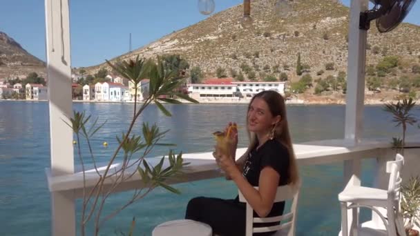 Mooie vrouw zitten in de waterkant met ananas sap — Stockvideo