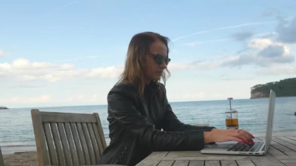 Молода жінка закінчує проект на ноутбуці у відкритому кафе — стокове відео