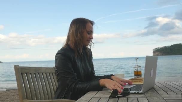 Mujer joven teniendo chat de vídeo en el ordenador portátil al aire libre — Vídeo de stock