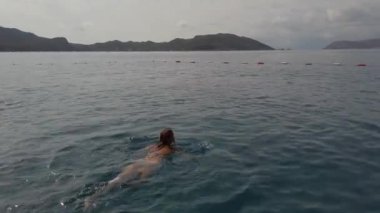 Genç bir kadın denizde yüzüyor.
