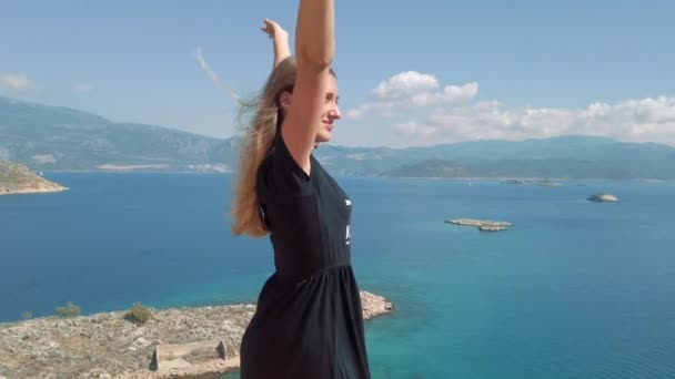 Femme en robe debout sur le bord de la falaise au-dessus de la mer — Video