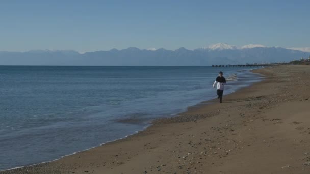 Mladý chlapec běží podél moře — Stock video