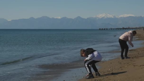 Moeder en zoon plukken schelpen — Stockvideo