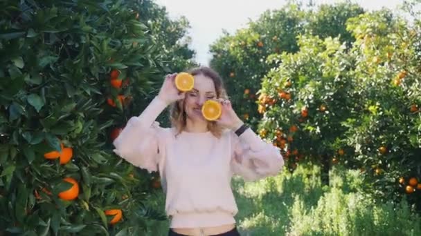 Genç ve güzel bir kadın gözlerinin önünde portakal tutuyor. — Stok video