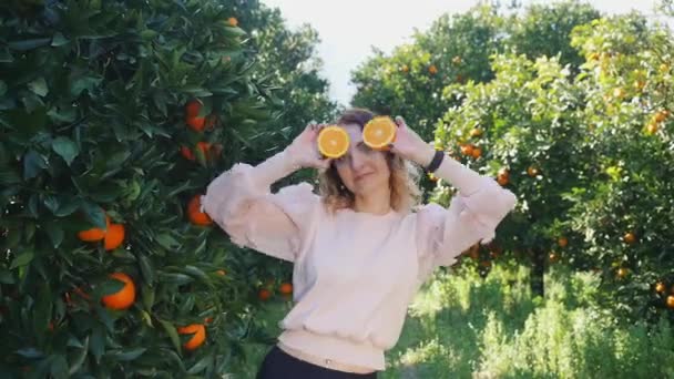 Wanita cantik muda memegang jeruk di depan matanya — Stok Video