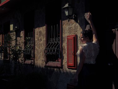 Taş binanın yanında duran kadın.