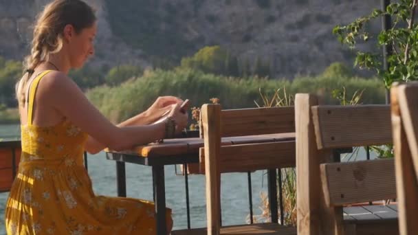 Kvinna med anteckningsbok nära floden — Stockvideo