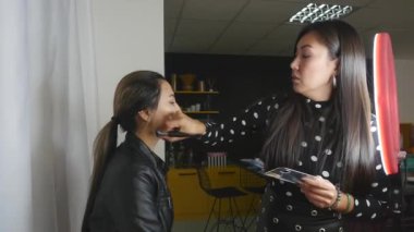 Maket yüzüne pudra süren profesyonel makyöz. 