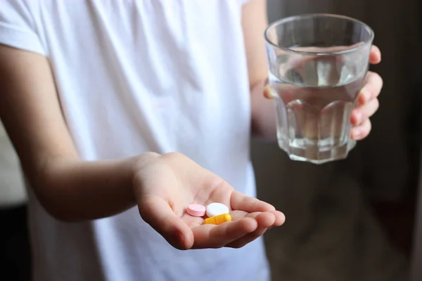 a pill and a glass of water in children's hands. pills in children's hands. children's diseases. concept of health.