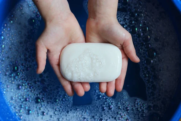 soap and soap foam in children\'s hands on a beautiful blue background. to wash hands. children\'s hygiene. hand hygiene.