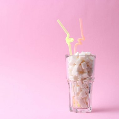 Saydam bir cam metin için yer pastel bir zemin üzerine şeker dolu. küp şeker. Minimalizm, diyabet, kalori, tatlı içecekler. 