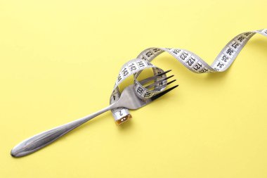 santimetre teyp ve metin eklemek için bir yer ile renkli bir arka plan üzerinde çatalı. minimalizm kompozisyon tarzı. Sağlık, kilo kaybı, diyet, doğru beslenme kavramı.