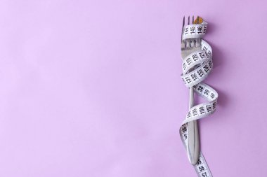 santimetre teyp ve metin eklemek için bir yer ile renkli bir arka plan üzerinde çatalı. minimalizm kompozisyon tarzı. Sağlık, kilo kaybı, diyet, doğru beslenme kavramı.