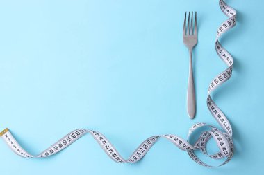 santimetre teyp ve metin eklemek için bir yer ile renkli bir arka plan üzerinde çatalı. minimalizm kompozisyon tarzı. Sağlık, kilo kaybı, diyet, doğru beslenme kavramı.