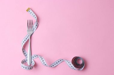 santimetre teyp ve metin eklemek için bir yer ile renkli bir arka plan üzerinde çatalı. minimalizm kompozisyon tarzı. Sağlık, kilo kaybı, diyet, doğru beslenme kavramı.