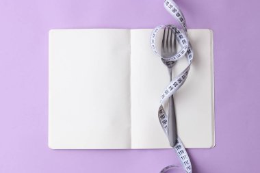 santimetre bant, defter ve metin alanı ile renkli bir arka plan üzerinde çatal. kavramı, sağlık, kilo kaybı, diyet, koloniler yanma, kilolu. minimalizm, üstten görünüm. flatlay 