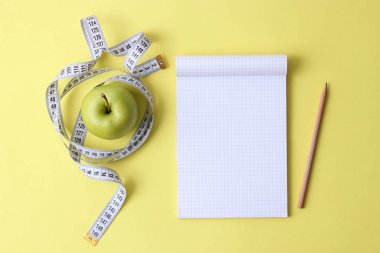 metin için yer ile renkli bir arka plan üzerinde santimetre bant, defter ve yeşil elma. kavramı, sağlık, kilo kaybı, diyet, koloniler yanma, kilolu. minimalizm, üstten görünüm. flatlay 