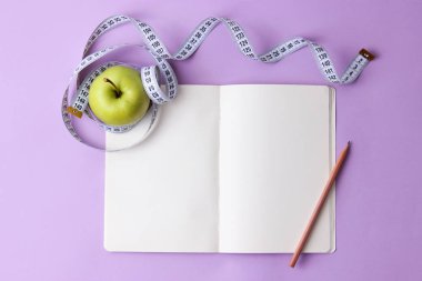 metin için yer ile renkli bir arka plan üzerinde santimetre bant, defter ve yeşil elma. kavramı, sağlık, kilo kaybı, diyet, koloniler yanma, kilolu. minimalizm, üstten görünüm. flatlay 