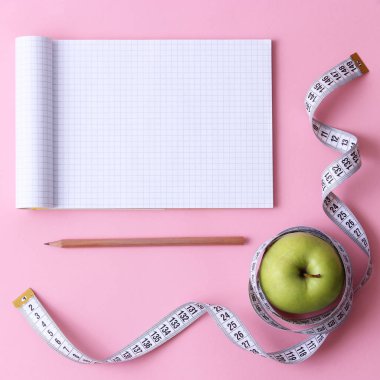 defter, yeşil elma ve santimetre kasette metin, en iyi görünüm için yer ile renkli bir arka plan. Konsept spor, diyet, fitness, planı, sağlıklı beslenme. 