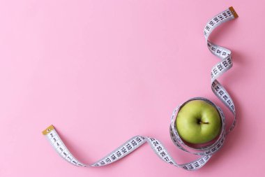 renkli bir arka plan metni eklemek için bir yer ile elma ve santimetre kasette. minimalizm, üstten görünüm. kavram diyet, sağlıklı beslenme, güzel vücut, spor.