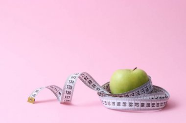 Elma ve santimetre bant renkli bir arka planda ve metni eklemek için bir yeri var. Minimalizm. konsept diyet, sağlıklı diyet, yağ yakma, kalori.