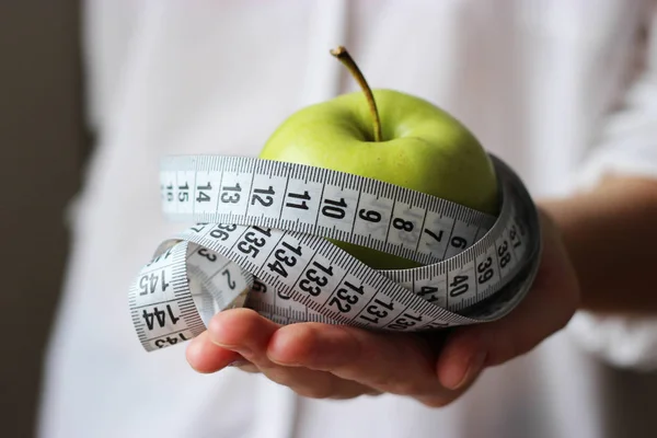 センチのテープと明るい背景に女性の手で緑のリンゴ ミニマリズム ダイエット フィットネス 健康的な栄養 ビタミン 健康体の概念 — ストック写真