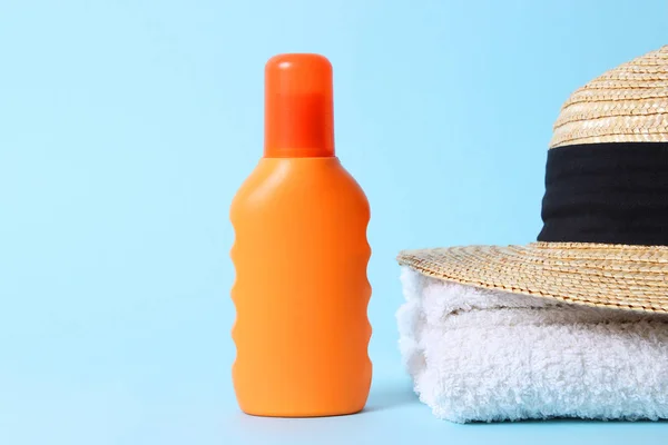 sunscreen, towel, hat on a colored background. Cosmetics for safe sunburn.