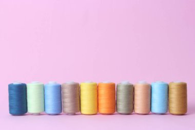 renkli bir arka plan üzerinde farklı renklerde dikiş ipliği.