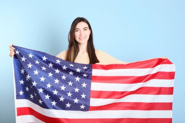 Amerika bayrağını renkli bir arka planda tutan güzel bir genç kız..
