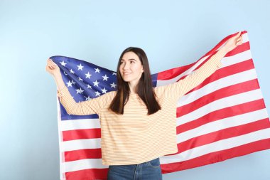 Amerika bayrağını renkli bir arka planda tutan güzel bir genç kız..