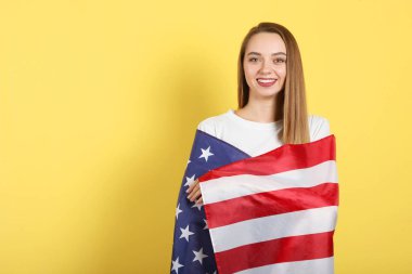 Amerika bayrağını renkli bir arka planda tutan güzel bir genç kız..