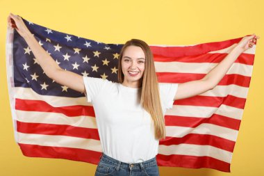 Amerika bayrağını renkli bir arka planda tutan güzel bir genç kız..