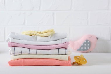 Hafif arka planda bebek kıyafetleri yığını.