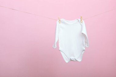 Renkli bir arka planda ipe bağlı bebek kıyafetleri. Bebek kıyafetlerini yıkama konsepti.