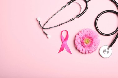 Pembe kurdele, gerbera ve steteskop renkli arka plan görüntüsü. Kadın kanserinin sembolü. Kadınlarda Kanser Farkındalığı