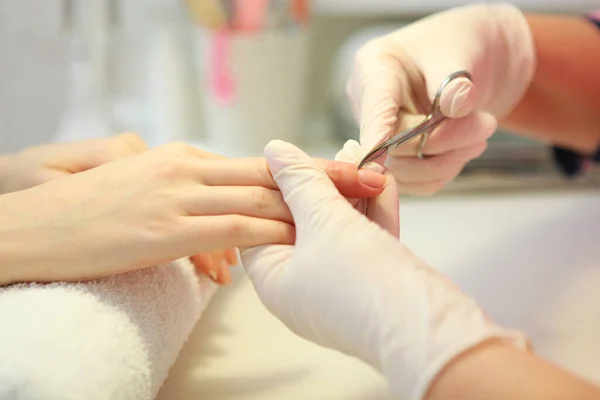 Closeup shot of a woman in a nail salon getting a manicure by a cosmetologist with a nail file. Woman gets a manicure of nails. Beautician puts nails on the client.