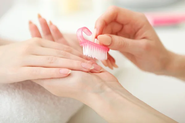 Closeup shot of a woman in a nail salon getting a manicure by a cosmetologist with a nail file. Woman gets a manicure of nails. Beautician puts nails on the client.