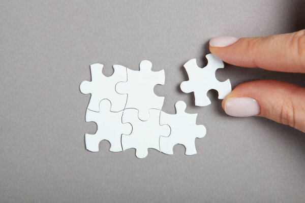 Collect puzzle. Hand and puzzle pieces on the table