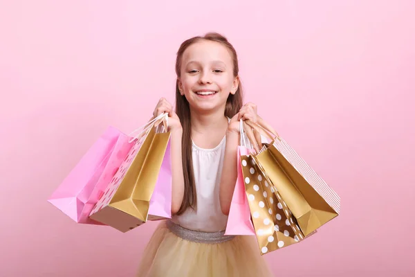 色の背景で買い物のための袋を持つ美しい笑顔の女の子 子供の買い物の概念 — ストック写真