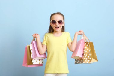 Renkli bir arka planda alışveriş yapmak için çantaları olan güzel, gülümseyen küçük bir kız. Çocuk alışverişi konsepti.