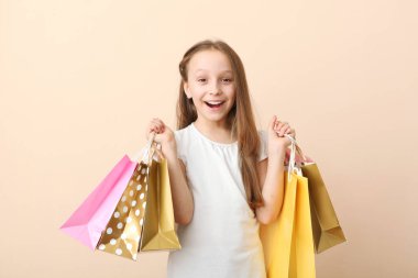 Renkli bir arka planda alışveriş yapmak için çantaları olan güzel, gülümseyen küçük bir kız. Çocuk alışverişi konsepti.
