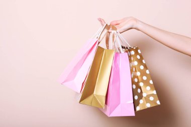 Renkli bir arka planda el ele alışveriş yapmak için poşetler. Alışveriş için kağıt torbalar. Metin ve minimalizm eklenecek bir yer.