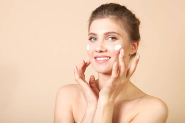 Renkli arka planda krem kullanan güzel bir genç kızın portresi. Sağlıklı cilt bakımı, kaplıca, cilt bakımı.