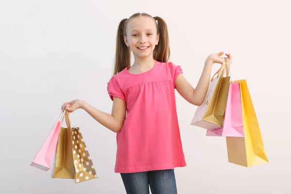 Hermosa Niña Sonriente Con Bolsas Para Compras Sobre Fondo Color —  Fotos de Stock